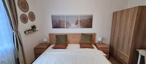 A bedroom with a bed, two bedside tables, a wardrobe, and wall art. - The Lume Flat – 2BR Family Apartment with Easy City Access (Prague)