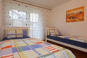 Ein Schlafzimmer mit zwei Betten, einem Fenster mit Vorhängen und einem Bild an der Wand.