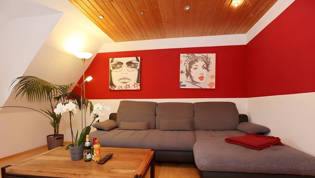 A modern living room with a brown sofa, a wooden coffee table, and two wall-mounted paintings. - Spacious Apartment – Private Covered Terrace, Garden, Playground Nearby (Villingen-Schwenningen)