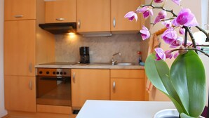 A kitchen with wooden cabinets, a stove, and a sink. - Spacious Apartment – Private Covered Terrace, Garden, Playground Nearby (Villingen-Schwenningen)