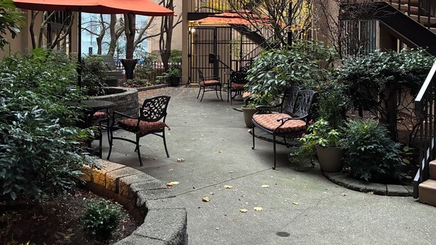 An outdoor patio area with seating, potted plants, and a staircase.