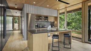Una cucina moderna con isola centrale, sgabelli da bar e vista sul verde.