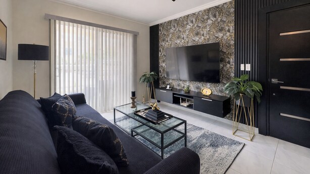 Una sala de estar moderna con un sofá, una mesa de centro, televisión y plantas decorativas.