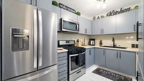 Una cocina moderna con electrodomésticos de acero inoxidable, armarios grises y un salpicadero blanco y negro.