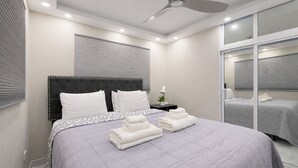 Un dormitorio moderno con una cama grande, mesitas de noche y un ventilador de techo.