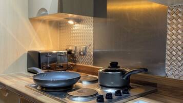 A modern kitchen with a gas stove, a frying pan, a pot, and a cutting board.