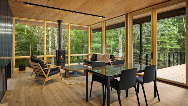 Een modern interieur met grote ramen, een open haard en een terras met een balustrade.