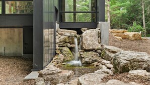 Een modern gebouw met een stenen waterval en uitzicht op het omliggende bos.