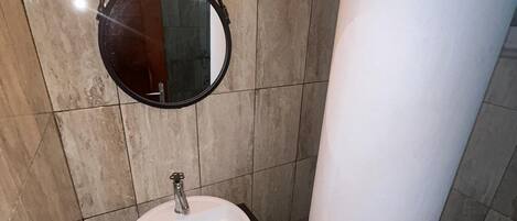A bathroom with a round mirror, a sink, and a towel rack.