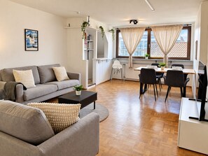 Ein modernes Wohnzimmer mit Sofa, Couchtisch und Essbereich mit Stühlen.