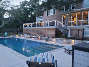 Ein Schwimmbecken mit Liegestühlen und einer mit Beleuchtung versehenen Poolterrasse.