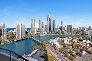 A cityscape with high-rise buildings, a waterfront, and a bridge.