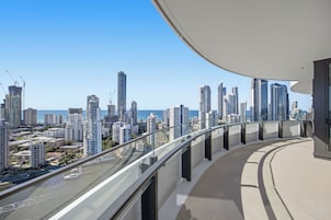 Un edificio alto con un balcón curvo que da a una vista panorámica de la ciudad y el mar.