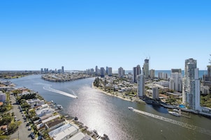 Un paisaje urbano costero con rascacielos, un puerto deportivo y una vía fluvial curvada.