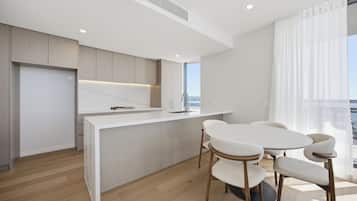 A modern kitchen with a white countertop, wooden cabinets, and a dining area with a round table and chairs.