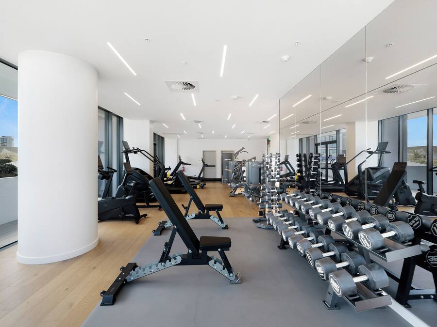 Ein modernes Fitnessstudio mit verschiedenen Trainingsgeräten, großen Fenstern und einem hellen, geräumigen Design.
