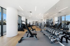 Un gimnasio moderno con diversos equipos de ejercicio, amplias ventanas y un diseño limpio y espacioso.