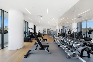 Un gimnasio moderno con diversos equipos de ejercicio, amplias ventanas y un diseño limpio y espacioso.