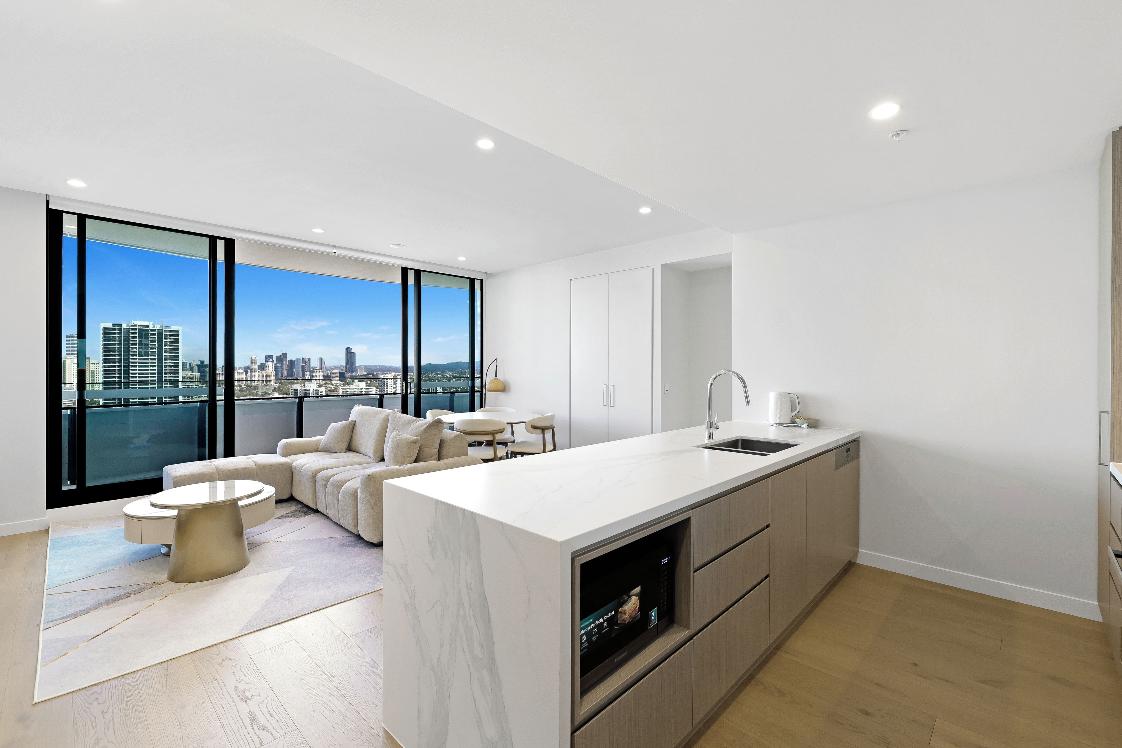 A modern kitchen with a large island, a dining area, and a sofa.