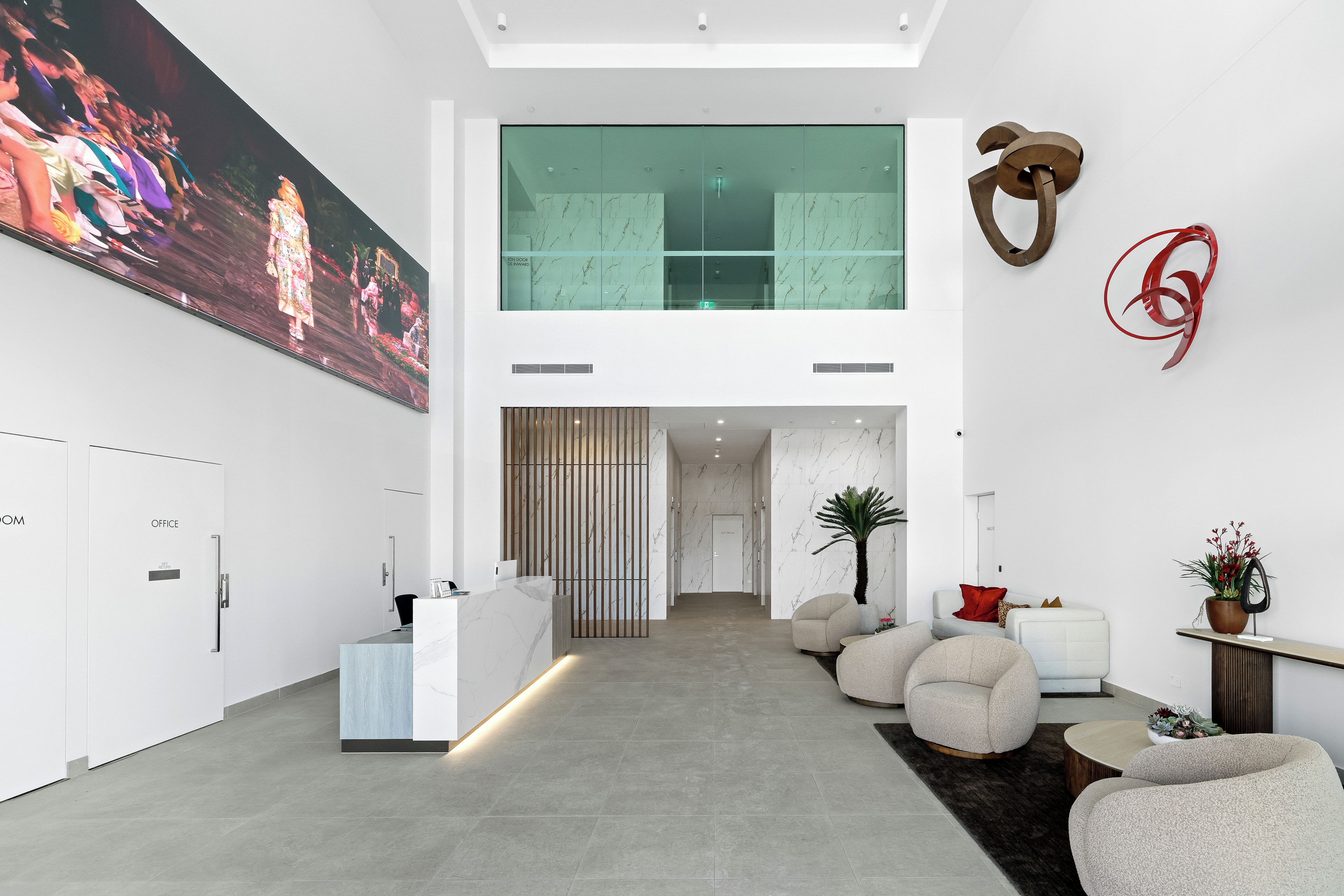 A modern lobby with a reception desk, seating area, and a large painting on the wall.
