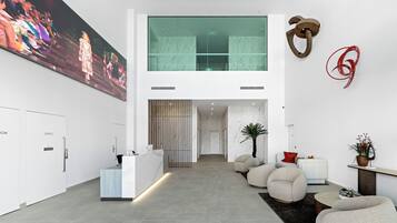 A modern lobby with a reception desk, seating area, and a large painting on the wall.