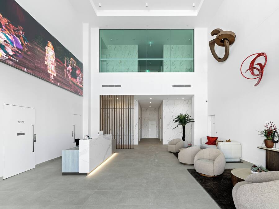 A modern lobby with a reception desk, seating area, and a large painting on the wall.