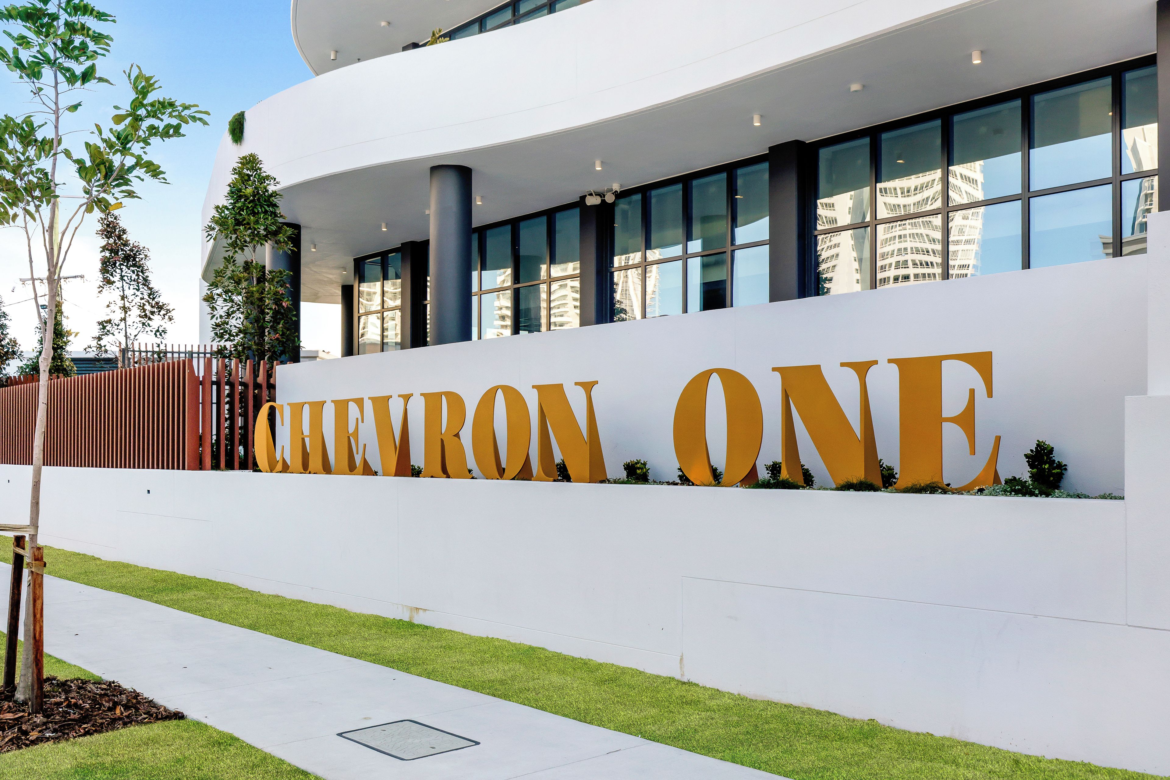 A modern building with a large sign reading 'CHEVRON ONE' and a well-maintained lawn in front.