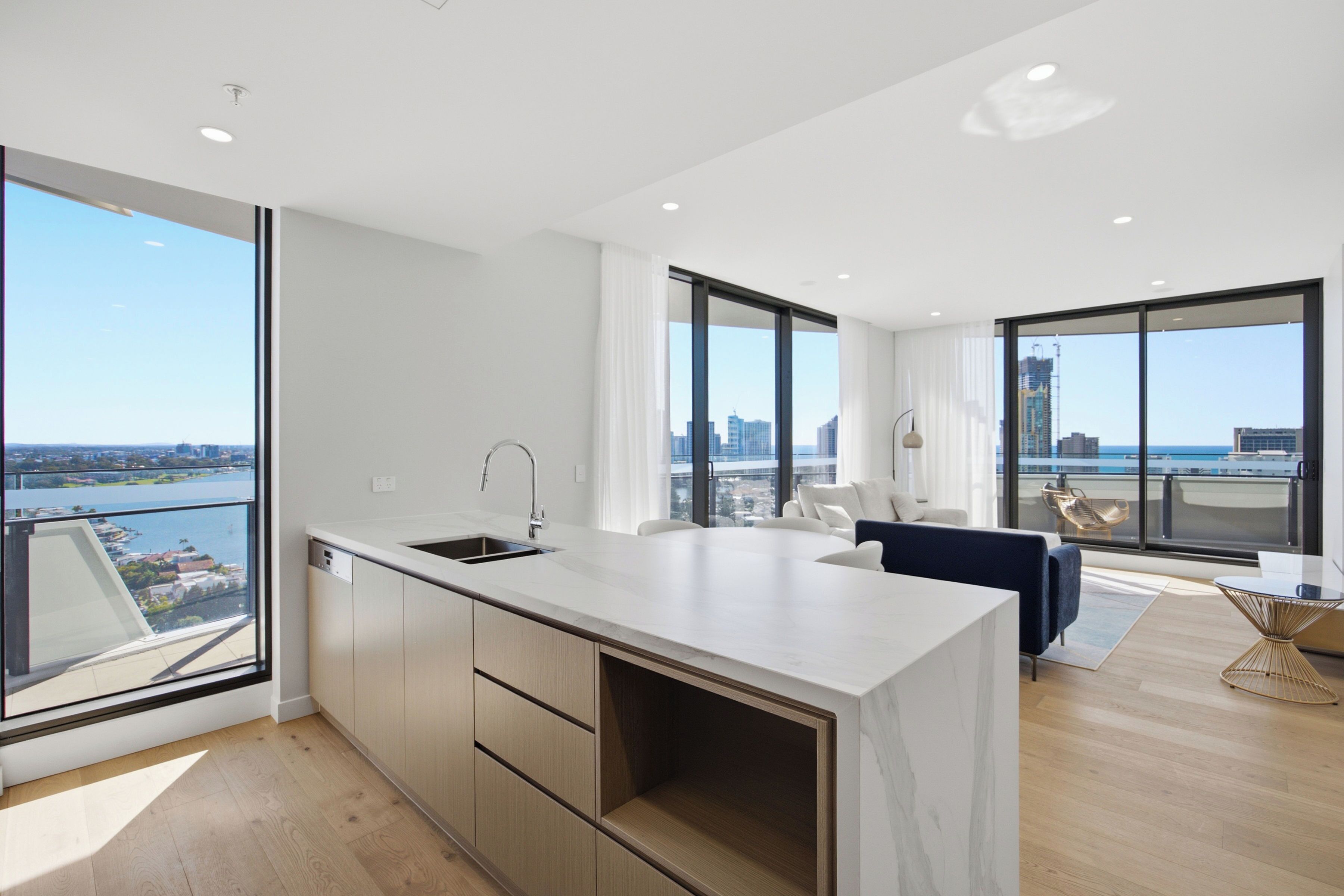 A modern kitchen with a large island, a dining area with a round table, and a view of the city through large windows.