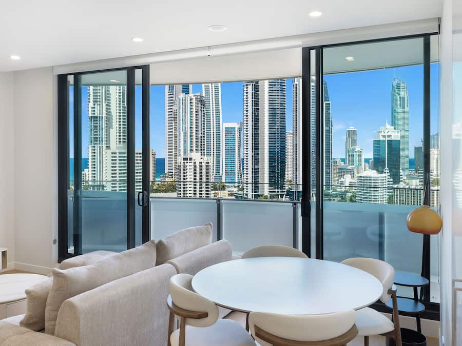 A modern living room with a large window, a round dining table, and a sofa.