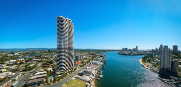 Un hotel moderno de gran altura con fachada curva, situado cerca de un muelle marítimo y un paisaje urbano al fondo.