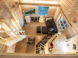 Ein Holzblockhaus-Innenraum mit einer Couch, einem Fernseher und einer Treppe.