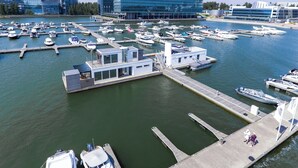 A marina with boats docked, a modern building in the background, and a small docked boat with a covered area.