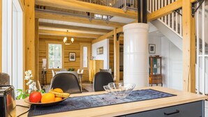 A wooden interior with a dining area, a staircase, and a kitchen counter with fruit.