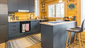 A modern kitchen with grey cabinets, a central island, and a bar stool.