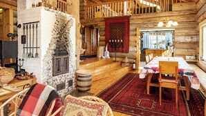 Ein Blockhaus-Interieur mit Kamin aus Stein, Holzmöbeln und einem Essbereich.