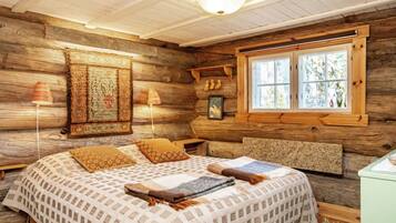 Un dormitorio de cabaña de troncos con una cama, dos lámparas, una ventana y un muro de madera.