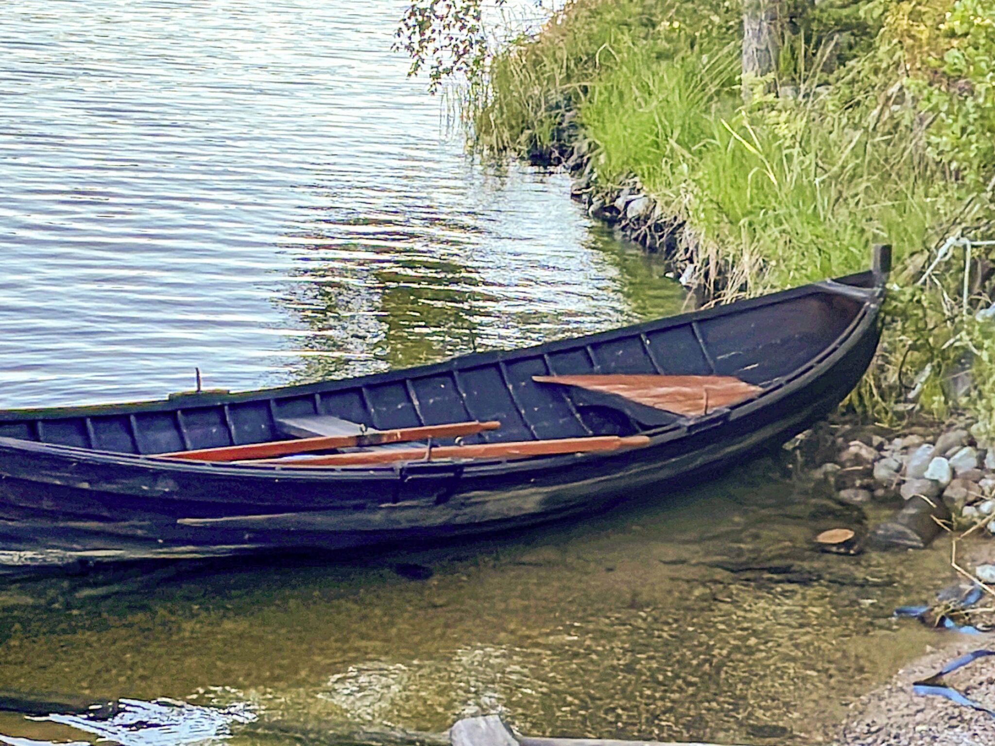 Een smalle waterweg met een roeiboot afgemeerd aan de oever.