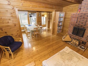 A wooden interior with a dining area, a bookshelf, and a fireplace.