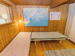 Puinen mökkimainen huone, jossa on kaksi sänkyä, seinällä kartta ja kalenteri.