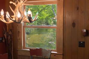 Ein Holzinnenraum mit einem großen Fenster, einer Kristallleuchtre und einem Sessel.