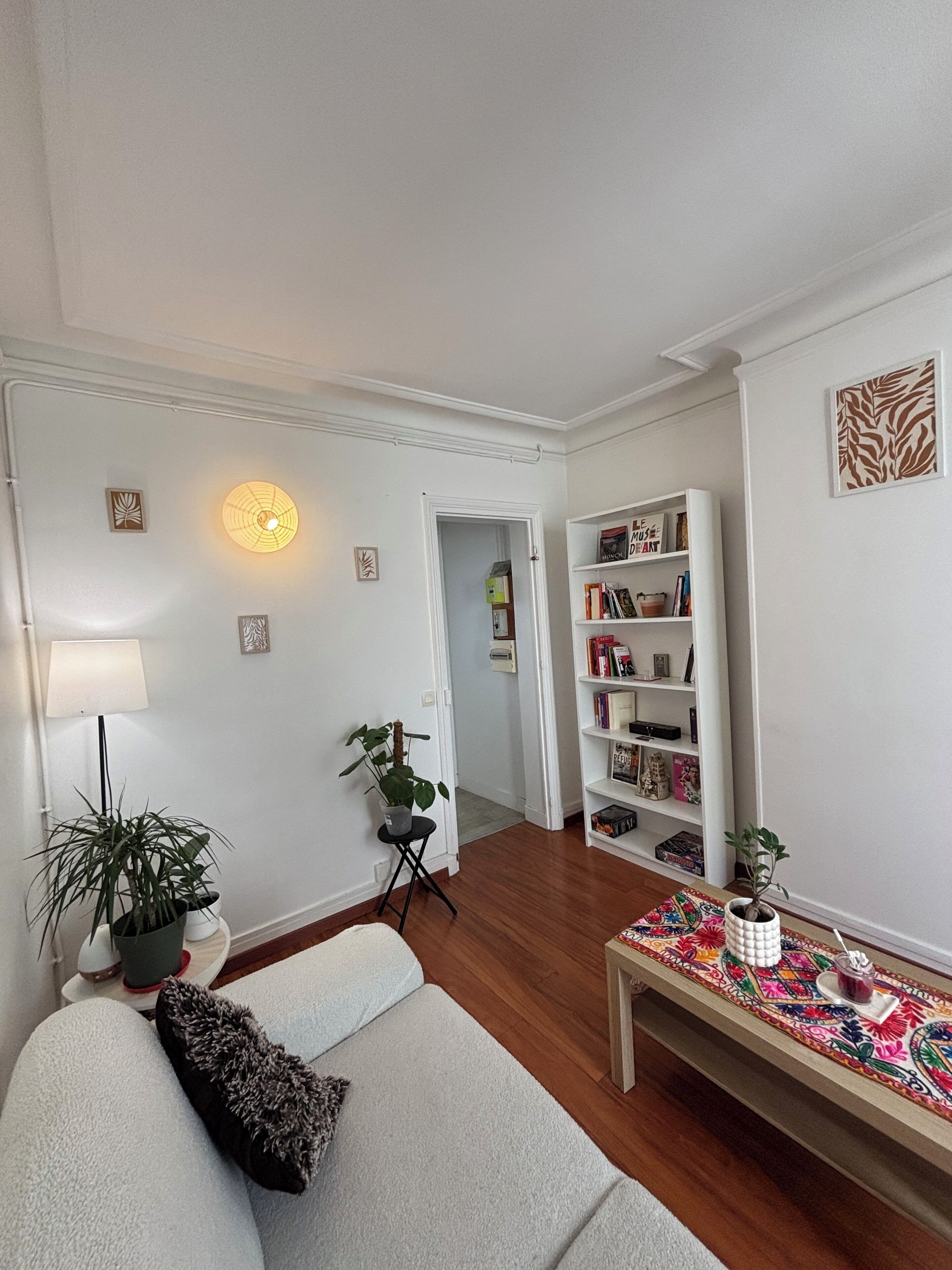 Una sala de estar con un sofá, una mesita de centro, una estantería y una planta en maceta.