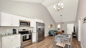 A modern kitchen with white cabinets, stainless steel appliances, and a dining area with a glass table and chairs. - Bright 2BR/2BA Home. Large Backyard, 5 Gig Fiber. Nr. VBC, Arsenal, Space Center (Huntsville)