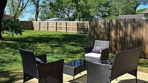 An outdoor patio with wicker furniture, a concrete floor, and a wooden fence in the background. - Bright 2BR/2BA Home. Large Backyard, 5 Gig Fiber. Nr. VBC, Arsenal, Space Center (Huntsville)