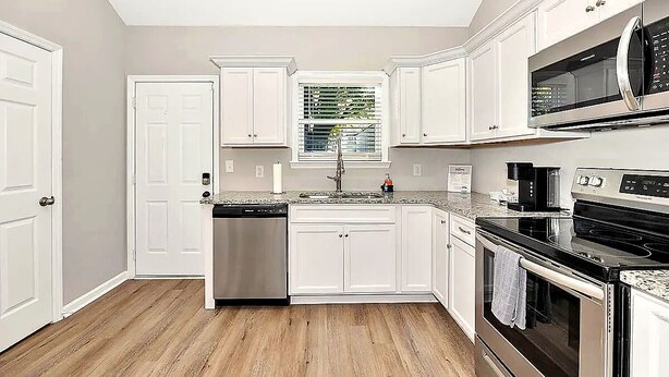 A kitchen with white cabinets, a dishwasher, a microwave, an oven, and a window with blinds. - Bright 2BR/2BA Home. Large Backyard, 5 Gig Fiber. Nr. VBC, Arsenal, Space Center (Huntsville)