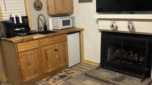 Une cuisine avec des meubles en bois, un four à micro-ondes, une machine à café et un petit réfrigérateur.