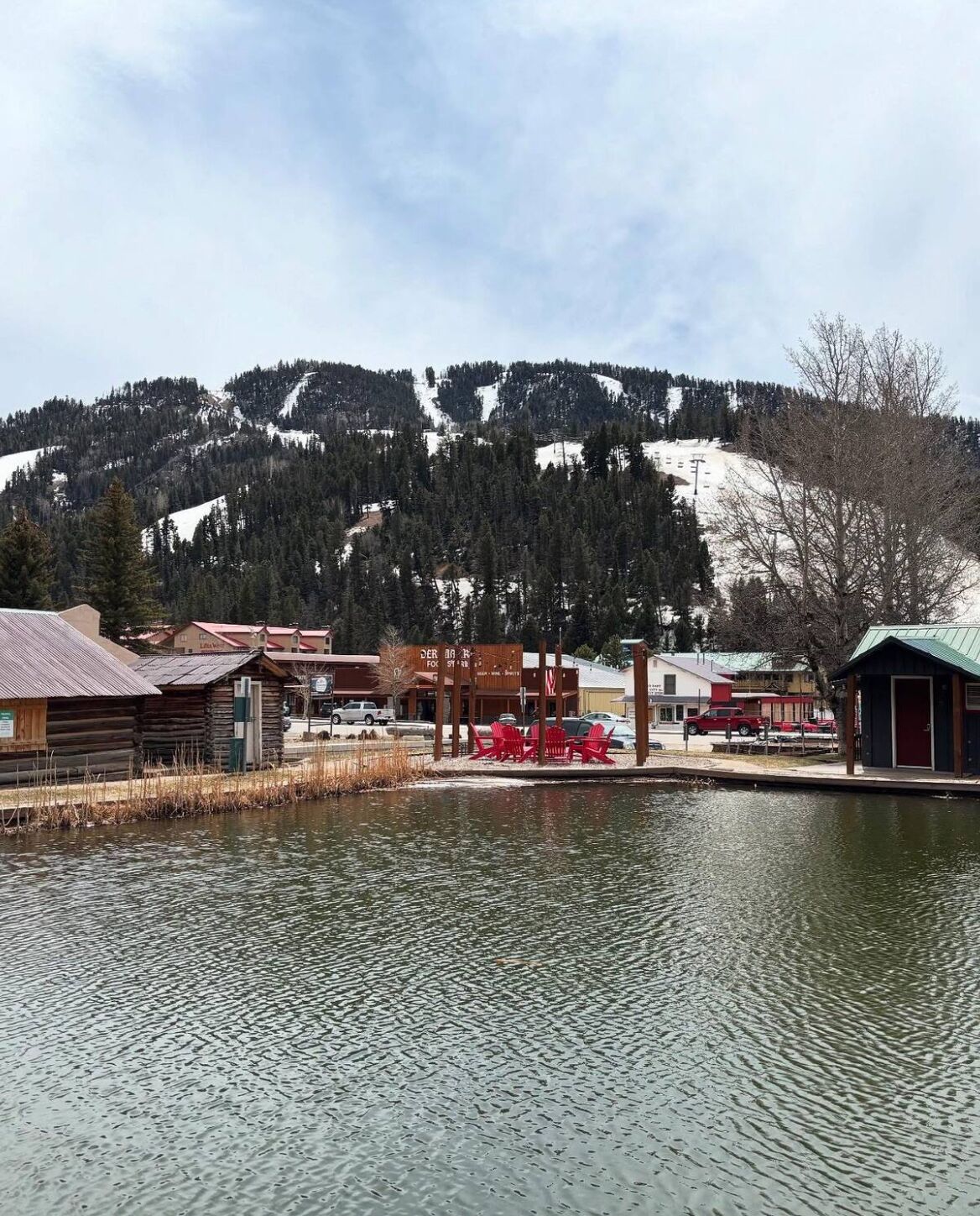 A lakeside view with cabins, a restaurant, and a mountain backdrop.