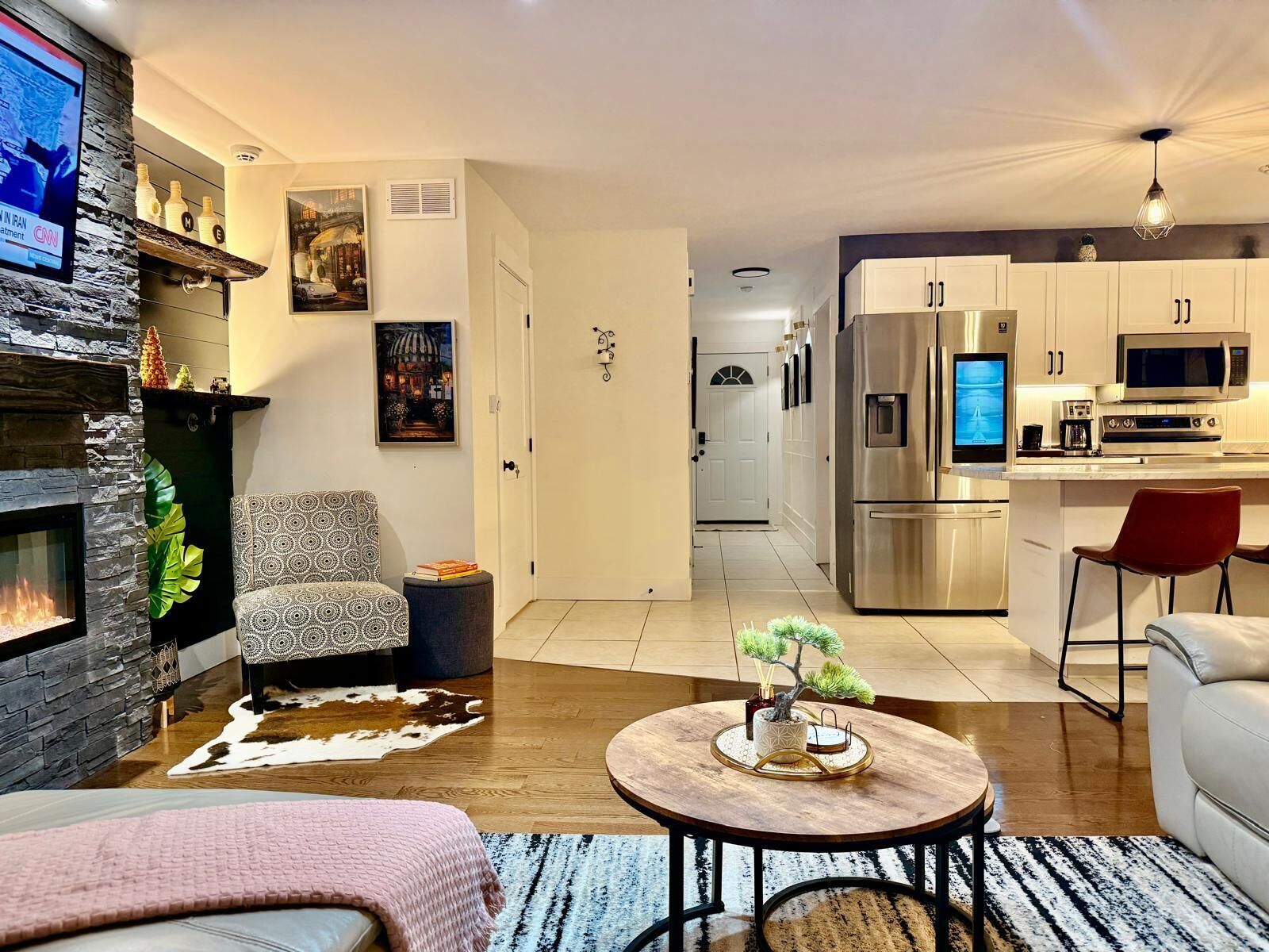 Een moderne woonkamer met een open haard, een eethoek en een keuken met roestvrijstalen apparatuur.