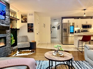 Uma sala de estar moderna com lareira, uma área de jantar e uma cozinha com eletrodomésticos de aço inoxidável.