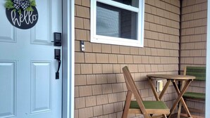 A front door with a 'hello' sign, a window, and a wooden chair outside. - High-end haven where Serenity meets Style and Fun| 5mins to airport| 5 car slots (Moncton)