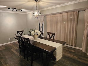 Comedor con mesa de madera, sillas, un jarrón con flores y una araña.